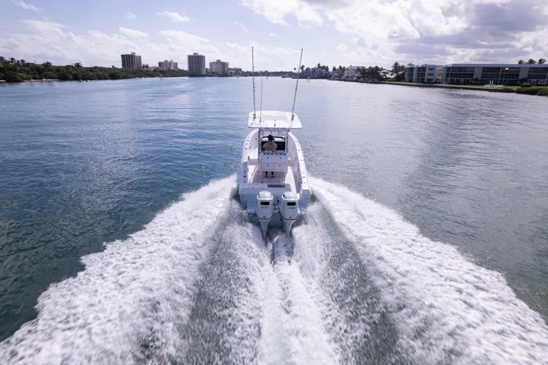 Slide: The Image of 2024 Bluewater 2550 boat cruising on a calm waterway with city skyline. - 2