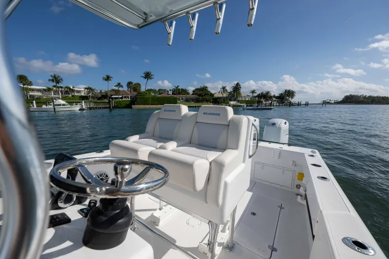 Slide: The Image of 2024 Bluewater 2550 boat with luxurious seating, steering wheel, and scenic waterfront view. - 35