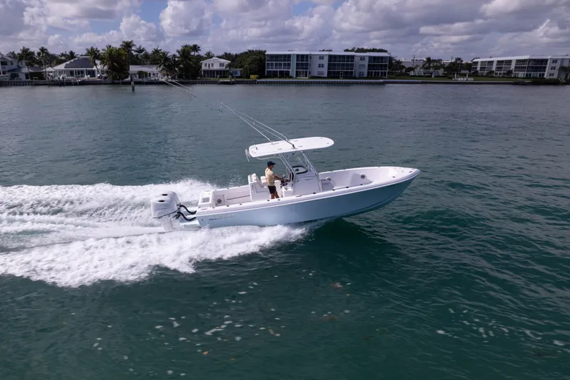 Slide: The Image of 2024 Bluewater 2550 boat cruising on a sunny day near waterfront homes. - 6