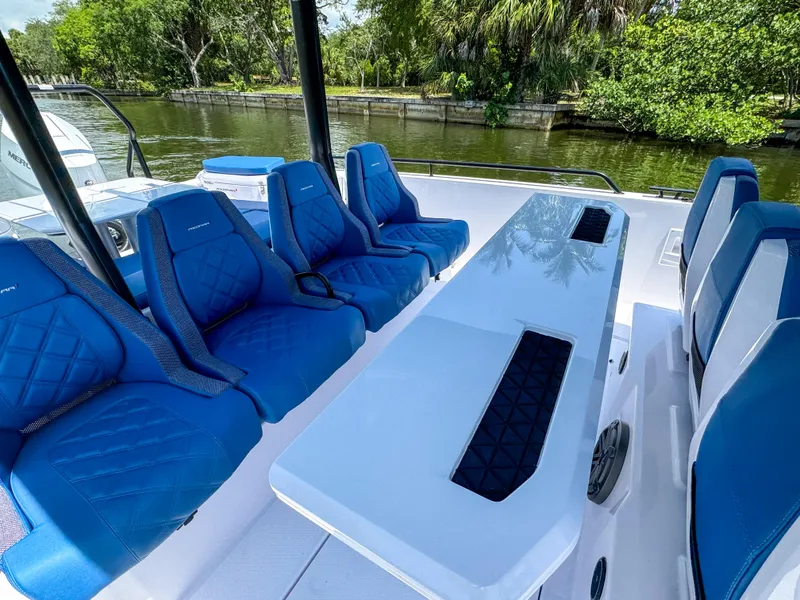 Slide: The Image of 2025 Axopar 37 Sun Top BRABUS Trim with blue seating and sleek table design. - 19