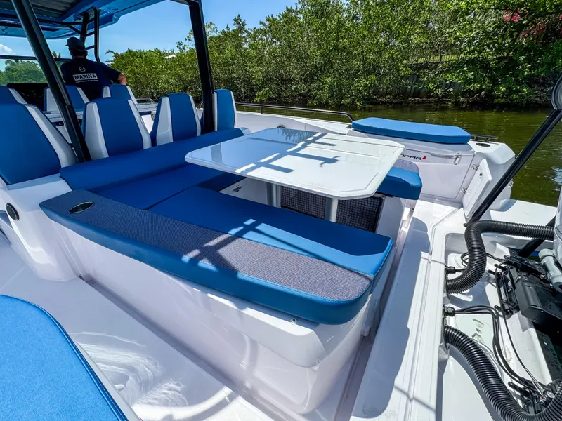 Slide: The Image of 2025 Axopar 37 Sun Top BRABUS Trim with blue seating and table on deck. - 9