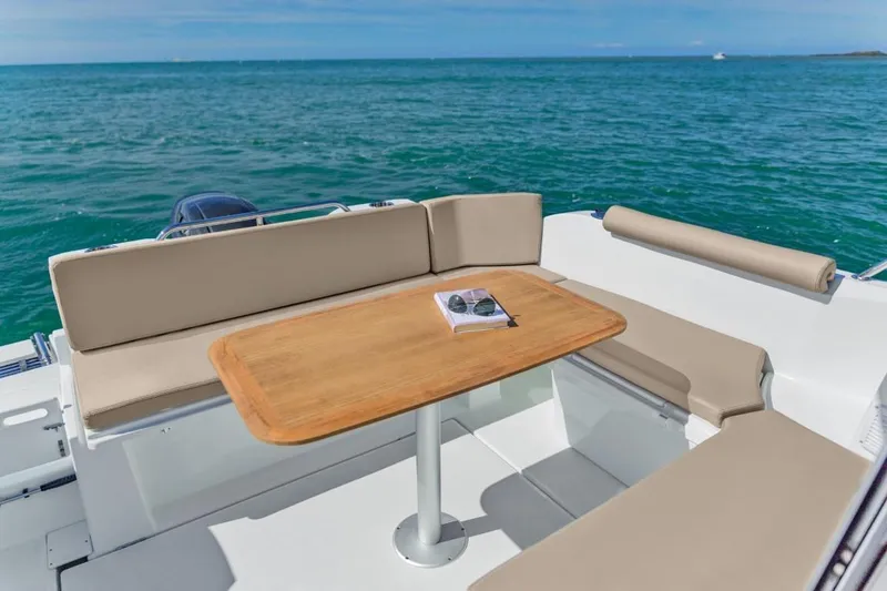 Slide: The Image of 2024 Beneteau America Antares 8 boat with outdoor seating and table on the water. - 9