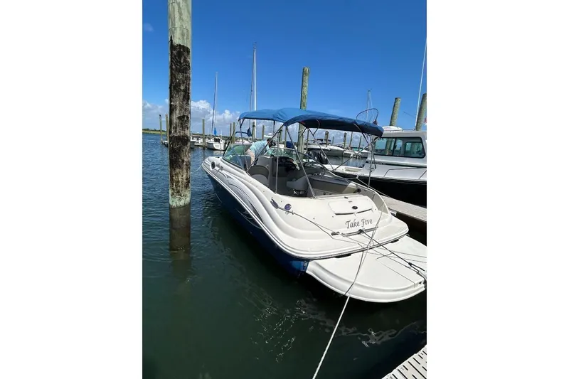 The Image of 2006 Sea Ray 240 Sundeck boat docked with blue canopy in marina. - 0