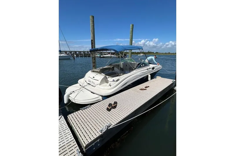 Slide: The Image of 2006 Sea Ray 240 Sundeck docked with blue canopy under clear sky. - 2