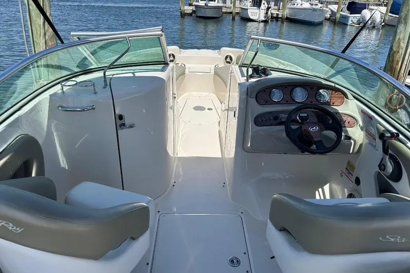 Slide: The Image of 2006 Sea Ray 240 Sundeck interior with steering wheel and seating, docked by the water. - 3