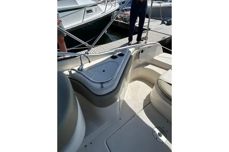 Slide: The Image of 2006 Sea Ray 240 Sundeck interior with seating and sink, docked at marina. - 6