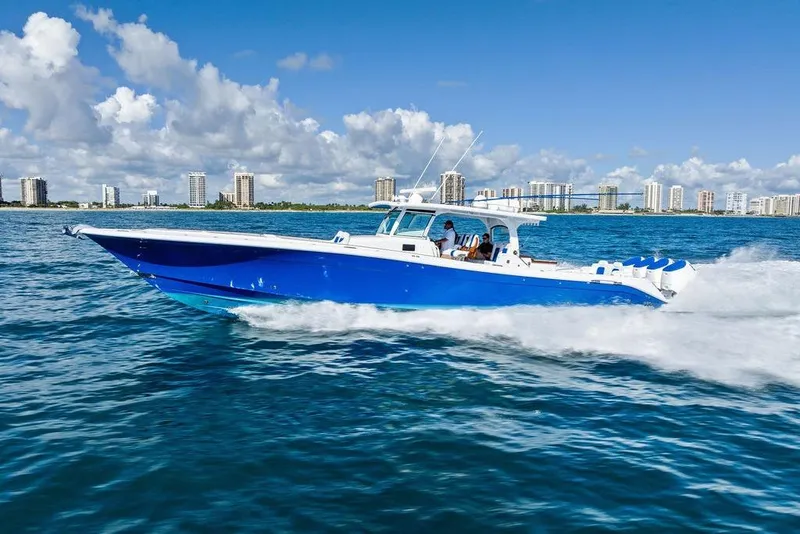 Slide: The Image of 2025 HCB 53 Suenos RXV boat cruising on blue ocean with city skyline backdrop. - 5