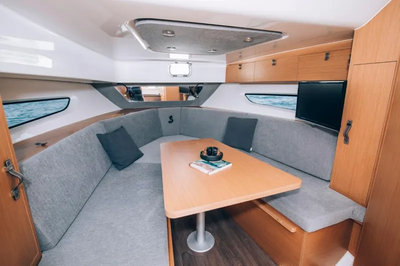 Slide: The Image of 2024 Beneteau Flyer 10 interior cabin with grey seating, wooden table, and TV. - 48