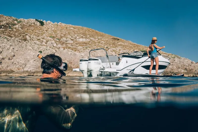Slide: The Image of 2024 Beneteau Flyer 10 near rocky shore with snorkeler and paddleboarder. - 12