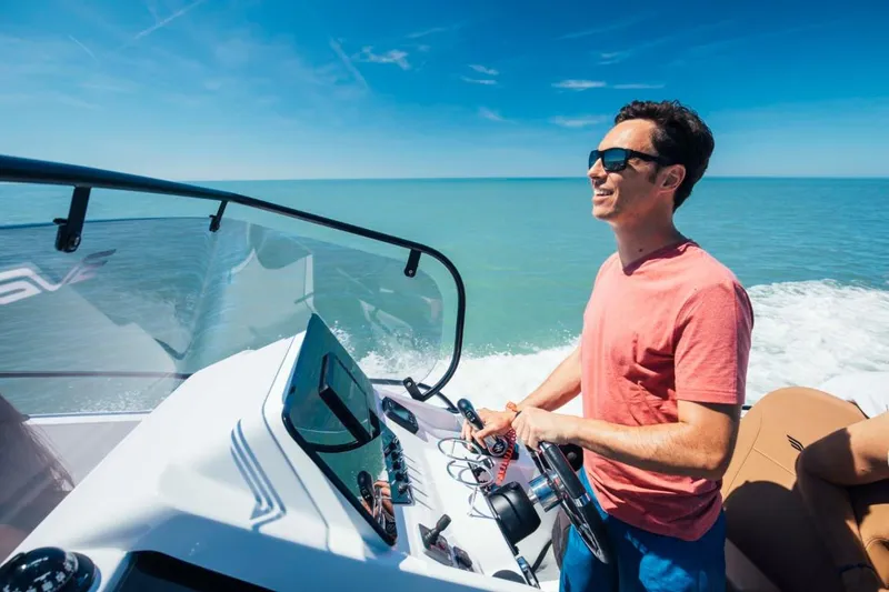 Slide: The Image of Man piloting 2025 Beneteau Flyer 8 SPACEdeck on open water, under clear blue sky. - 15