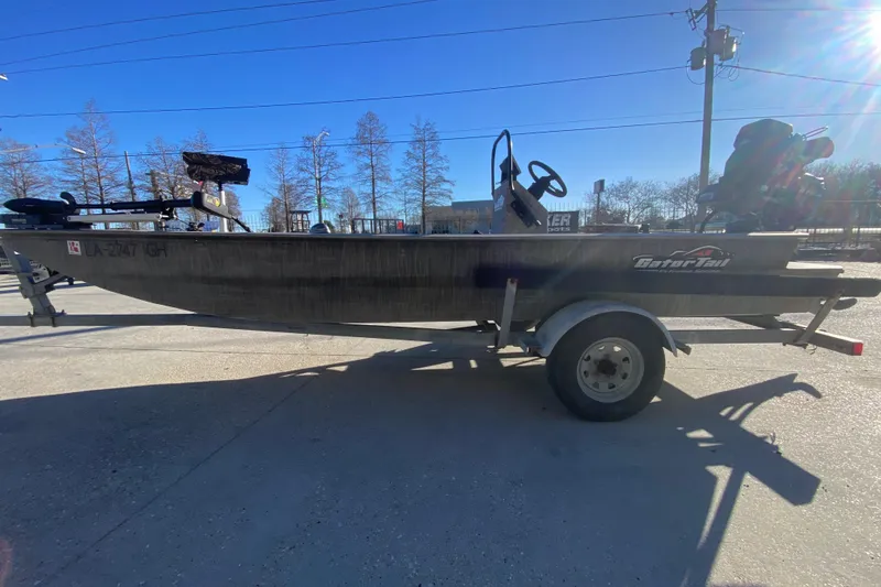 Slide: The Image of 2018 Gator Tail 17' boat on trailer, parked outdoors under clear blue sky. - 6
