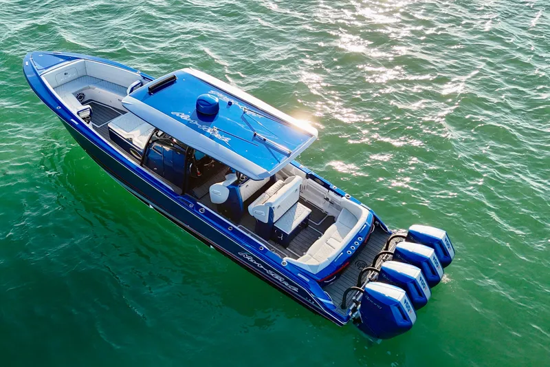 Slide: The Image of 2026 Nor-Tech 390 Sport Center Console boat on shimmering water, featuring four powerful engines. - 11