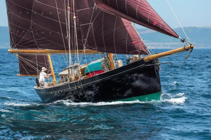 The Image of Sailing boat "Mayflower 50" from 2012 navigating ocean waters with maroon sails. - 0