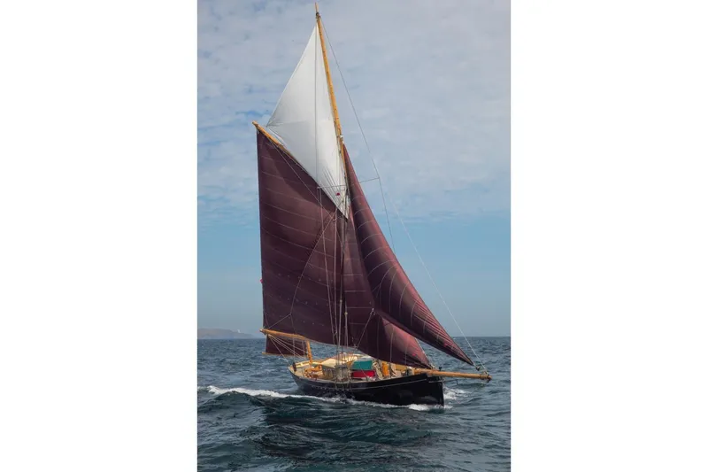 Slide: The Image of Custom Mayflower 50 sailboat from 2012 with maroon sails on open sea. - 1