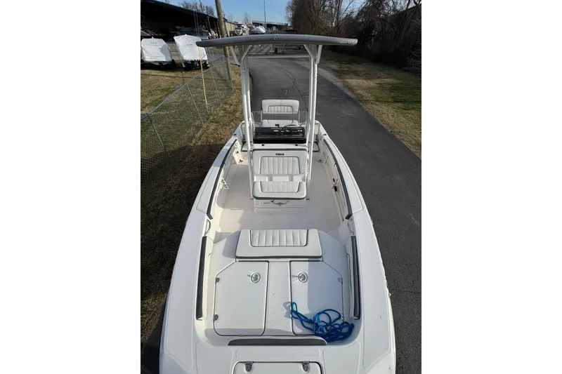 Slide: The Image of 2017 Yamaha Boats 190 FSH Sport, white deck, T-top, parked on pavement. - 6