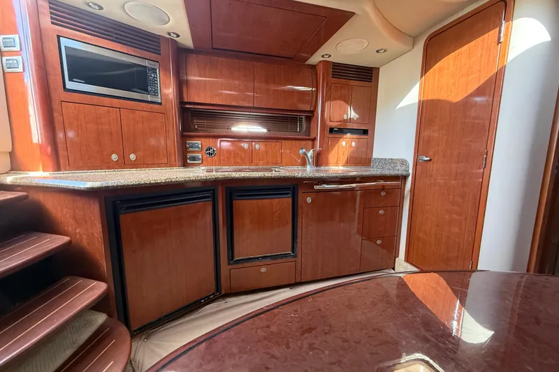 Slide: The Image of 2005 Sea Ray 390 Sundancer interior with wood cabinetry and modern kitchen amenities. - 18
