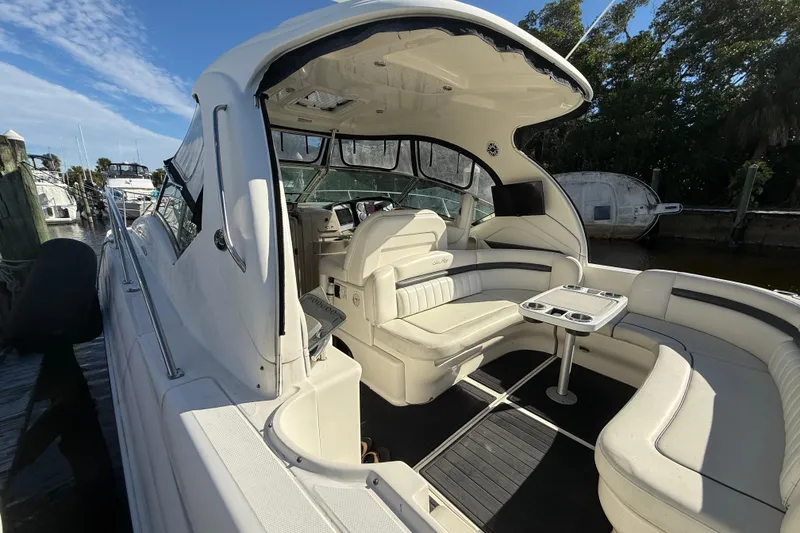Slide: The Image of 2005 Sea Ray 390 Sundancer yacht interior with white seating and table, docked by the water. - 5