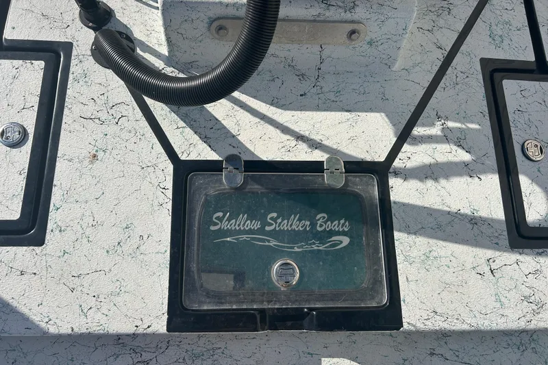 Slide: The Image of Shallow Stalker Cat 240 Pro Elite 2021 boat deck with logo and storage compartments. - 13