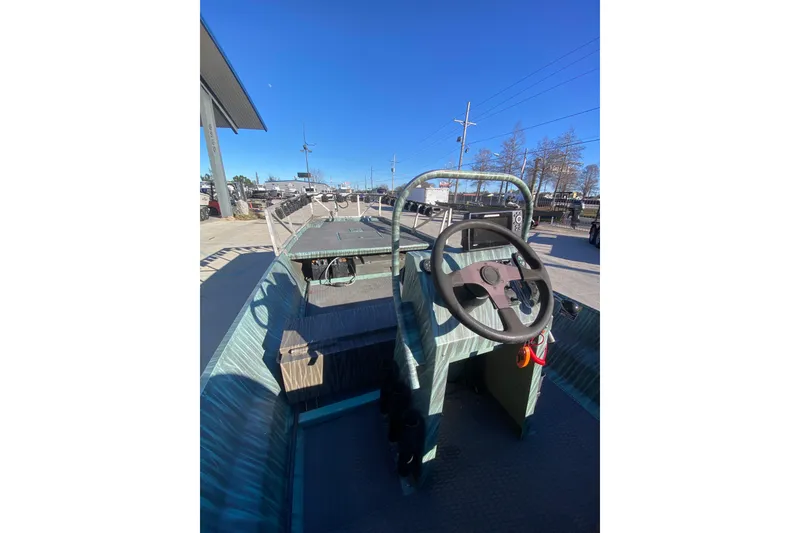 Slide: The Image of 2015 Gator Tail 18' boat with steering wheel, parked outdoors under clear blue sky. - 21