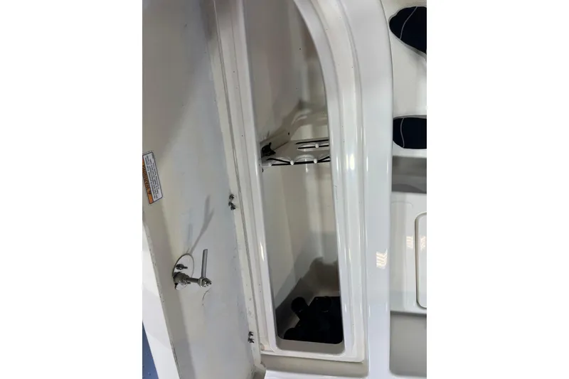 Slide: The Image of 2023 NauticStar 227 XTS boat storage compartment with latch and interior view. - 18