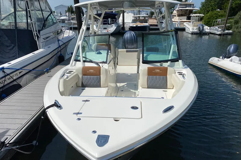 Slide: The Image of 2022 Cobia 240 Dual Console boat docked in a marina, showcasing sleek design and spacious seating. - 2