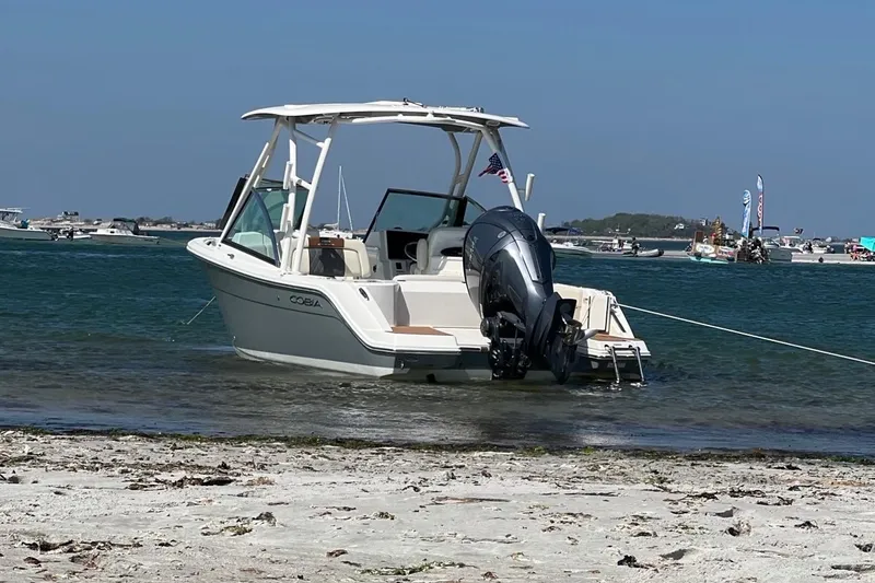 Slide: The Image of 2022 Cobia 240 Dual Console boat anchored on a sandy beach with clear blue water. - 7