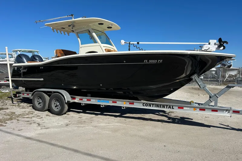 The Image of 2016 Scout 275 LXF boat on trailer, black hull, sunny day. - 0