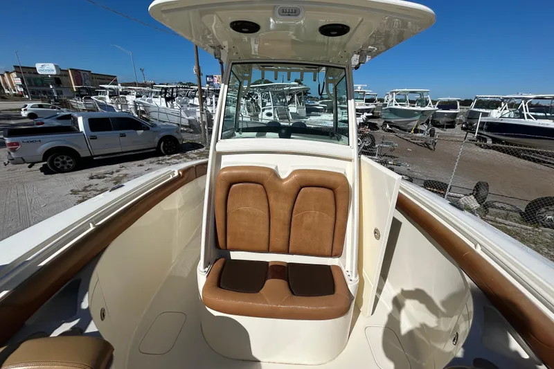 Slide: The Image of 2016 Scout 275 LXF boat interior with tan seating, parked in a marina. - 17