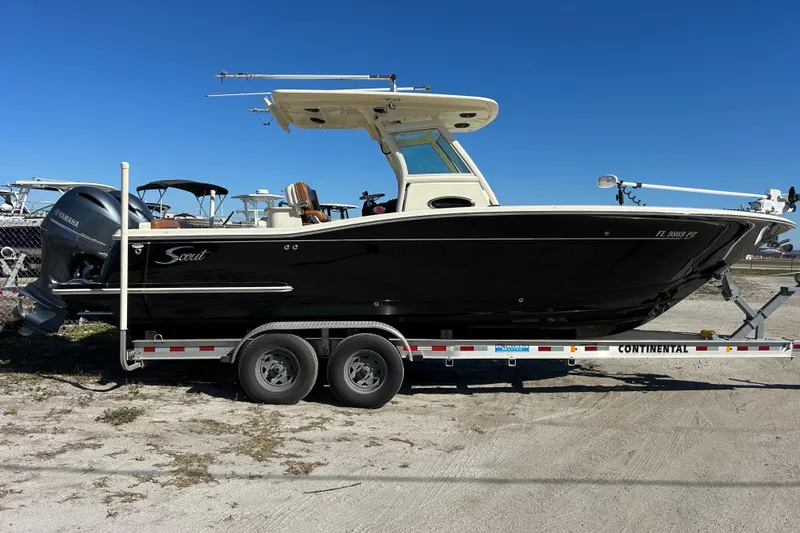 Slide: The Image of 2016 Scout 275 LXF boat on trailer, side view, clear blue sky background. - 2