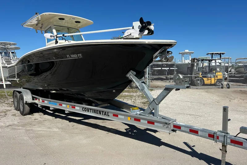 Slide: The Image of 2016 Scout 275 LXF boat on trailer, parked outdoors under clear blue sky. - 22