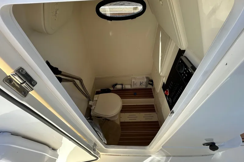 Slide: The Image of Interior of 2016 Scout 275 LXF boat showing compact bathroom with toilet and control panel. - 25