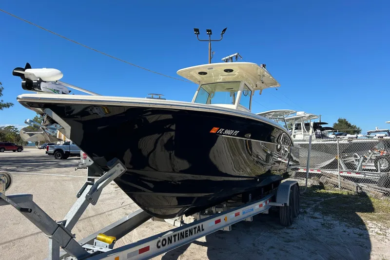 Slide: The Image of 2016 Scout 275 LXF boat on trailer under clear blue sky. - 3
