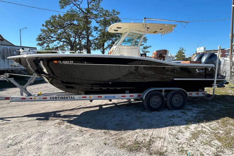 Slide: The Image of 2016 Scout 275 LXF boat on trailer, parked outdoors under clear blue sky. - 4