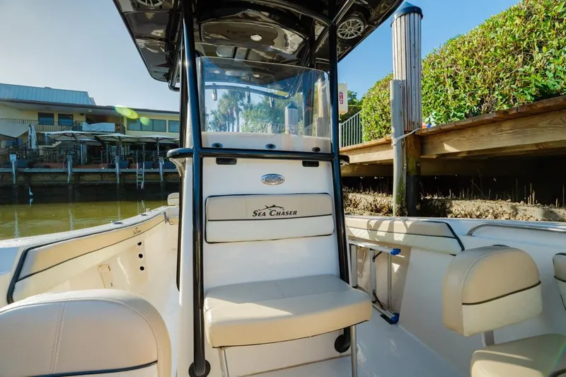 Slide: The Image of 2022 Sea Chaser 24 HFC boat interior with seating and console, docked by waterfront. - 10
