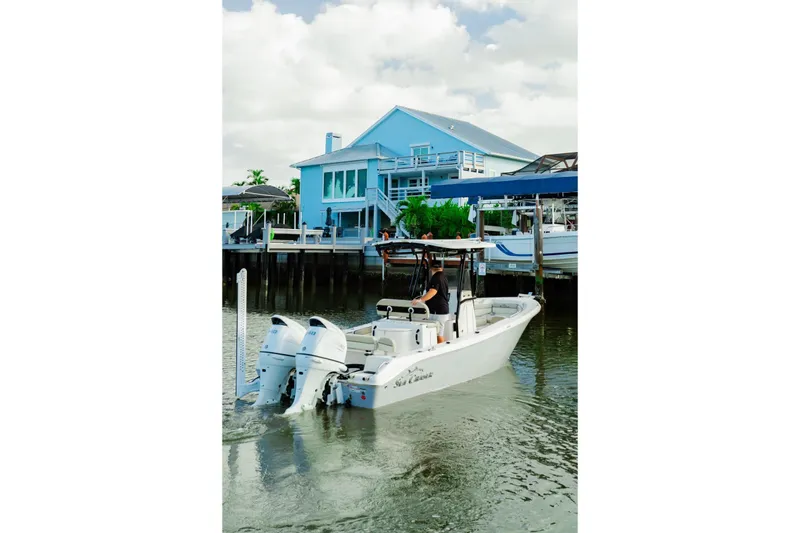 Slide: The Image of 2022 Sea Chaser 24 HFC boat near a blue waterfront house. - 2