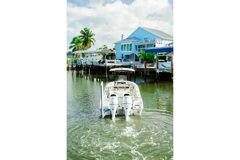 Slide: The Image of 2022 Sea Chaser 24 HFC boat cruising near waterfront homes under a cloudy sky. - 7