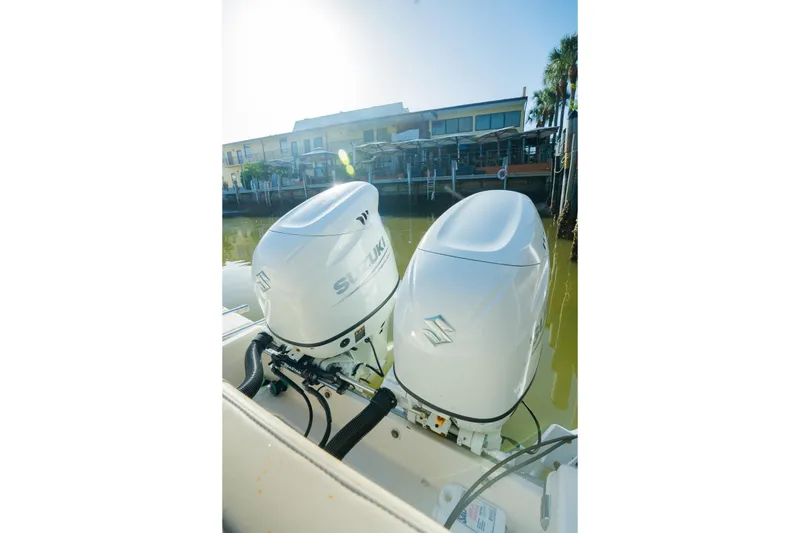 Slide: The Image of Twin Suzuki outboard engines on a 2022 Sea Chaser 24 HFC boat docked by waterfront buildings. - 9