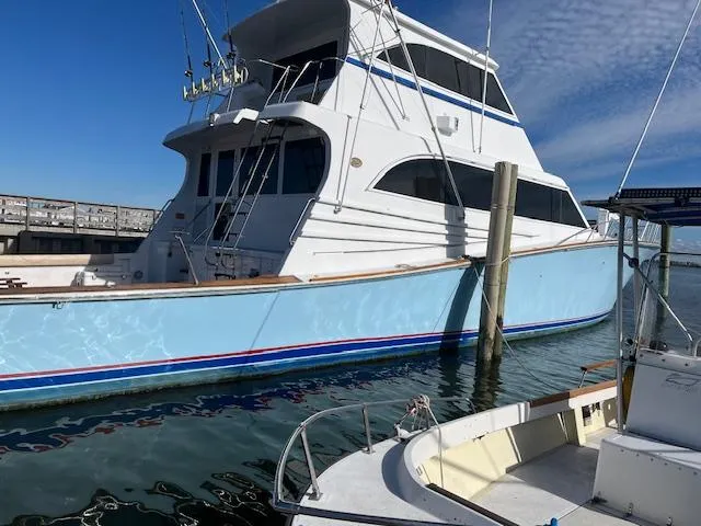 The Image of 1992 Huckins 70 Convertible yacht docked at marina under clear blue sky. - 0