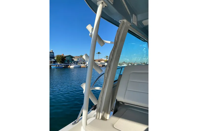Slide: The Image of 2021 Boston Whaler 345 Conquest interior with rod holders, overlooking waterfront homes. - 17