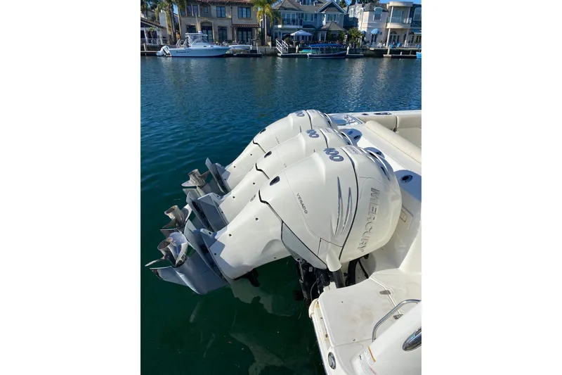 Slide: The Image of 2021 Boston Whaler 345 Conquest with triple Mercury outboard engines docked by waterfront homes. - 2