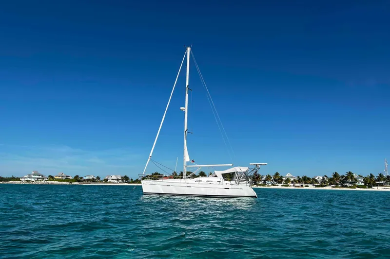 Slide: The Image of 2007 Beneteau 393 sailboat anchored in a serene, turquoise bay under a blue sky. - 36