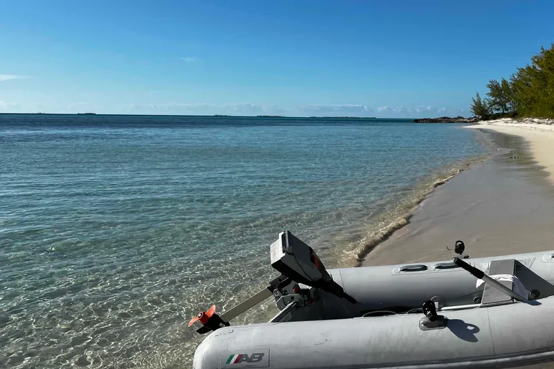 Slide: The Image of Sailboat anchored in a serene bay, surrounded by lush islands and clear blue waters. - 37