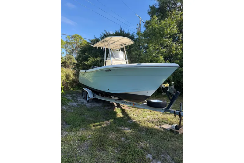 The Image of 2022 Cobia 220 Center Console boat on trailer, parked in a residential driveway. - 0