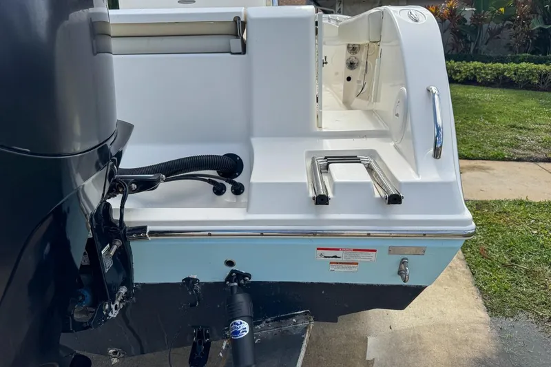 Slide: The Image of 2022 Cobia 220 Center Console boat with motor and swim ladder, docked on concrete. - 11