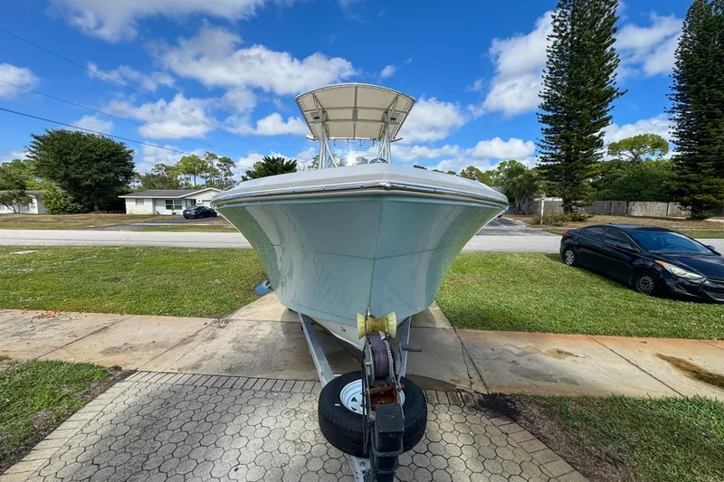 Slide: The Image of 2022 Cobia 220 Center Console boat on trailer, parked in driveway under blue sky. - 16