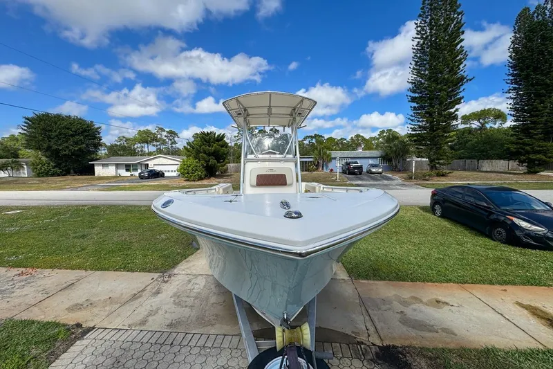 Slide: The Image of 2022 Cobia 220 Center Console boat parked in a suburban driveway under a blue sky. - 17