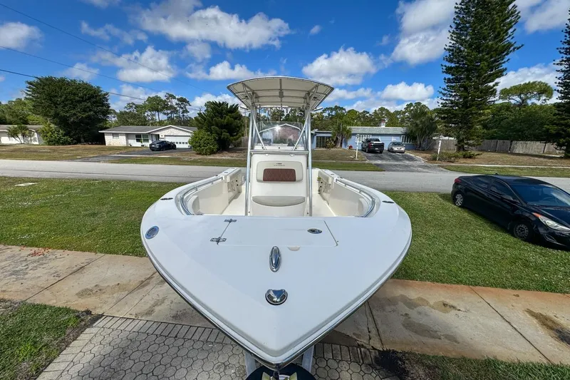 Slide: The Image of 2022 Cobia 220 Center Console boat parked in a suburban driveway under a blue sky. - 18
