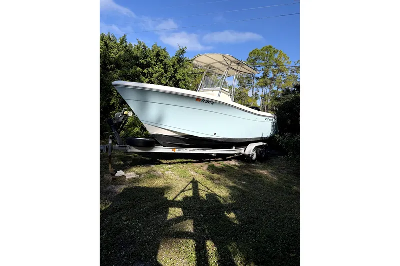 Slide: The Image of 2022 Cobia 220 Center Console boat on trailer with Mercury engine, parked outdoors. - 2