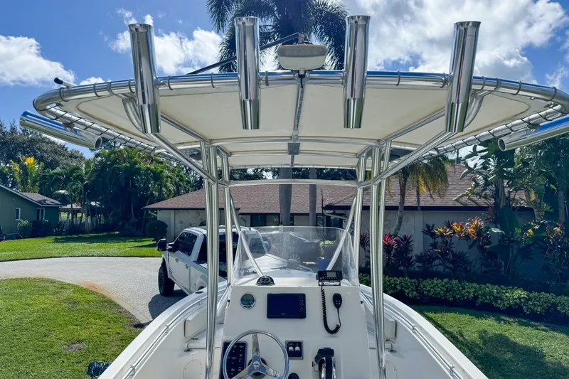 Slide: The Image of 2022 Cobia 220 Center Console boat with T-top and rod holders in a residential driveway. - 22