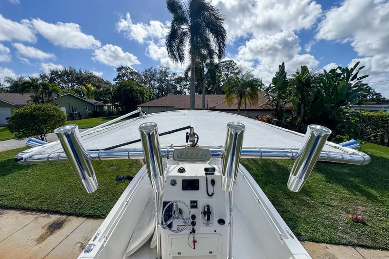 Slide: The Image of 2022 Cobia 220 Center Console boat with rod holders, parked in a sunny residential area. - 24